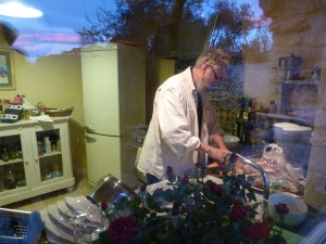 Looking through the window at Tim cooking, the sunset reflected above