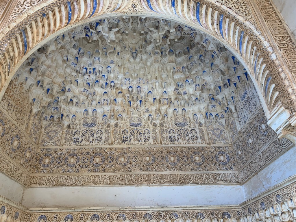 A ceiling dome made of marble and lapiz lazuli, with many small carved arches, geometric designs and Arabic epigraphy.