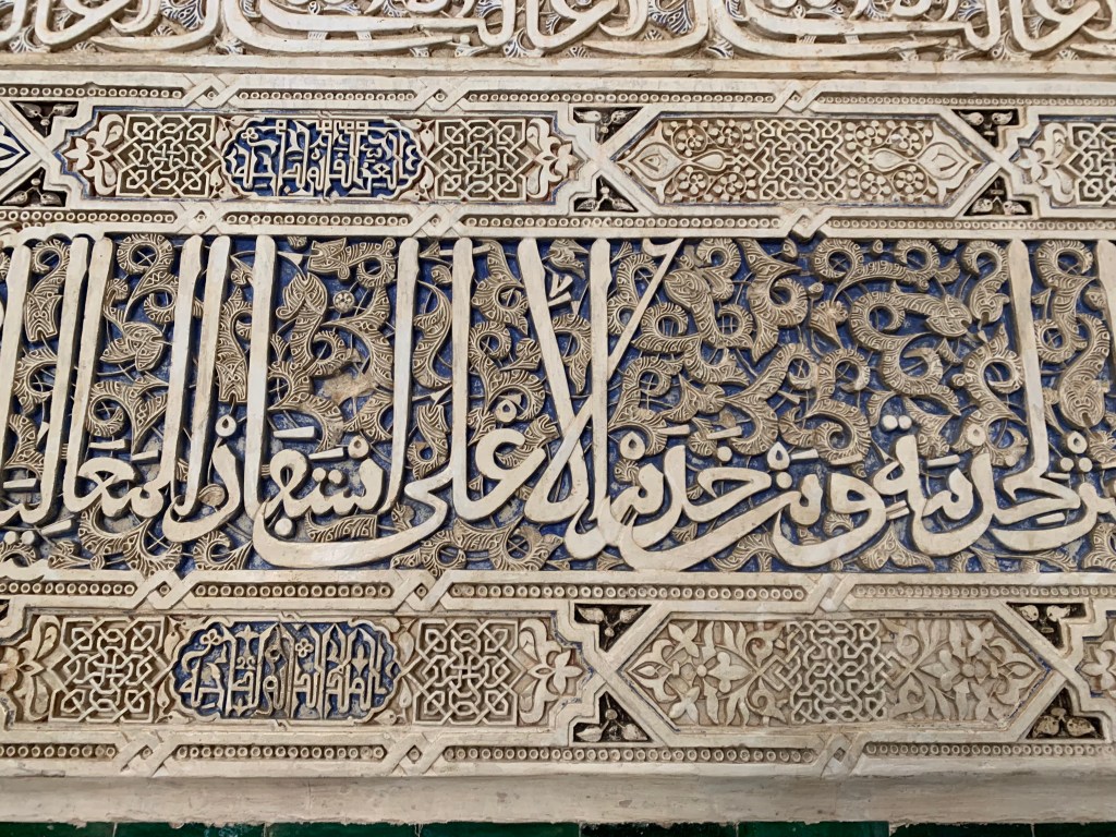 Close up of carved Arabic epigraphy with lapis lazuli behind