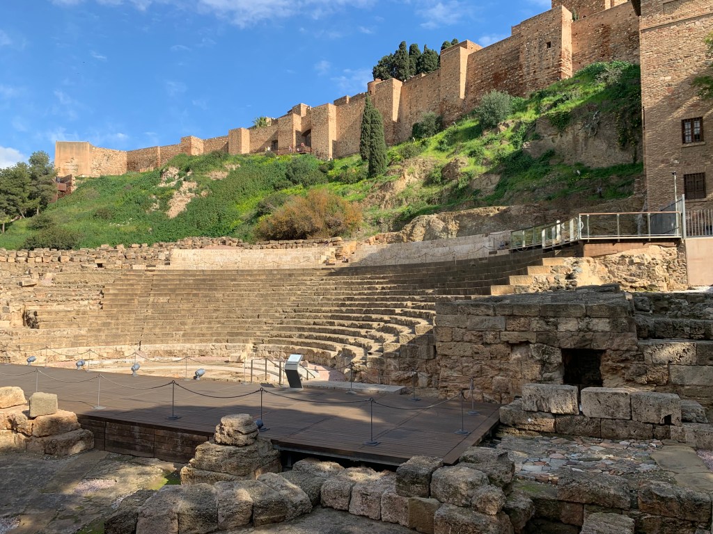 Roman Amphitheatre carved into the rock. Stone walled fortress above.