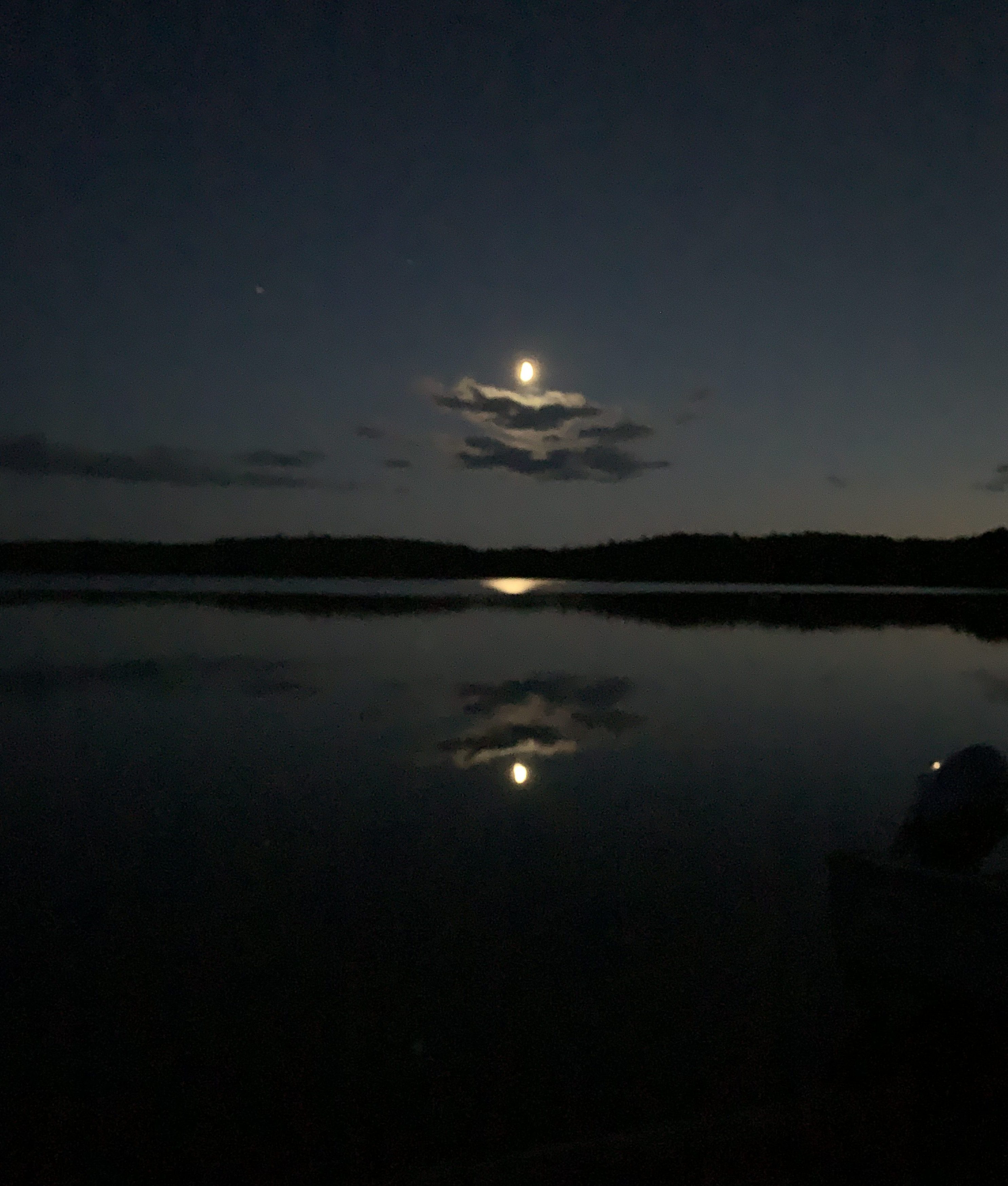 The moon rising and reflecting on a lake.